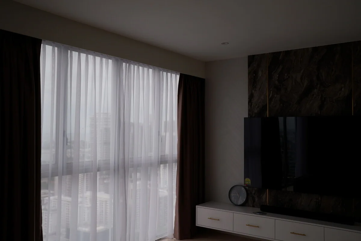 Sheer curtains beside a living room television wall