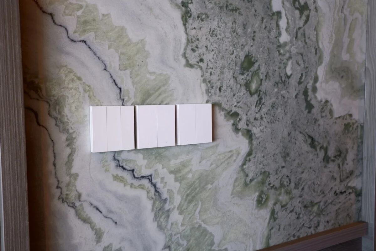 White wall switches fitted against a patterned stone finish